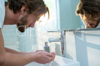 Man washing his face with water in bathroom