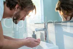 Man washing his face with water in bathroom