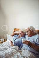 Senior woman using digital tablet and man having cup of coffee