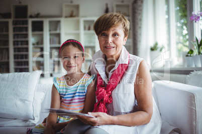 Portrait of senior woman and her granddaughter holding a photo album
