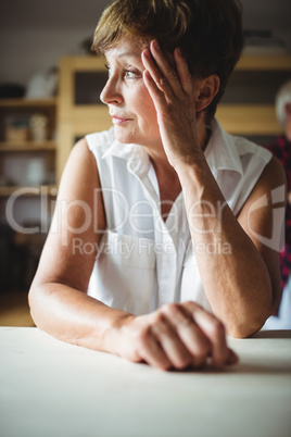 Worried senior woman leaning on table