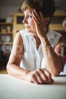 Worried senior woman leaning on table