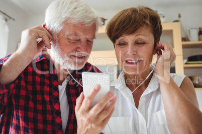 Senior couple listening to music on smartphone