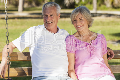 Happy Senior Couple Sitting on Bench in Sunshine