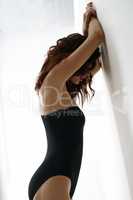 Side view of sensual brunette posing against wall