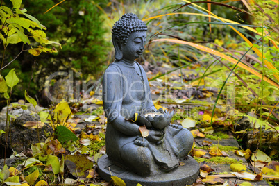 bunter Herbst im Garten an einem Teich mit einem Buddha