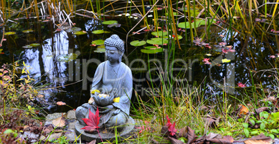 bunter Herbst im Garten an einem Teich mit einem Buddha
