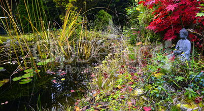 bunter Herbst im Garten an einem Teich mit einem Buddha