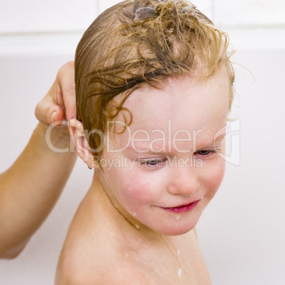 Child sits in the bath with the hair wash