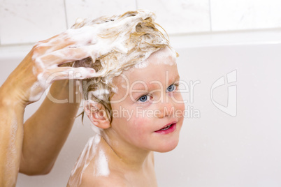 Child sits in the bath with the hair wash