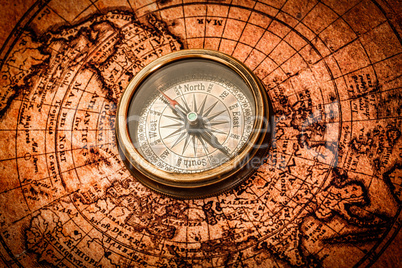 Vintage compass lies on an ancient world map.