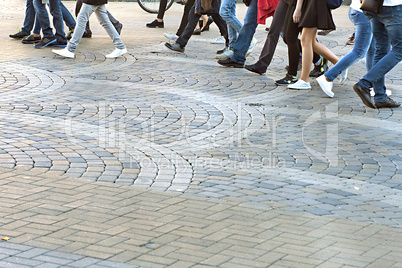 set of feet of people walking on the sidewalk