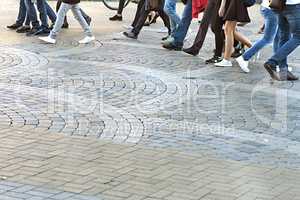 set of feet of people walking on the sidewalk