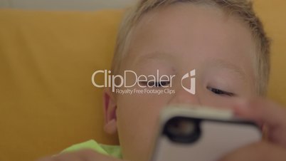 Close-up shot of little boy playing a game on the smartphone