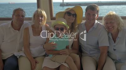 Happy family child mother father grandparents are sitting on closed deck of boat
