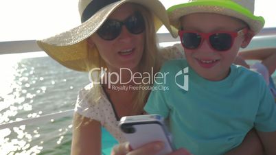 young woman and son are watching something in smartphone in riding motor boat