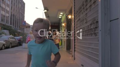Little boy runs along a busy street of Thessaloniki, Greece