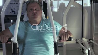Close-up of grown man in gym performs exercises chest press
