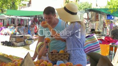 Young family in market of Thessaloniki, Greece choose peaches