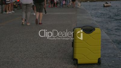 Suitcase on wheels stands on sea coast in city of Thessaloniki, Greece