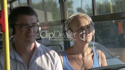 Woman and man listening music in headset during bus trip