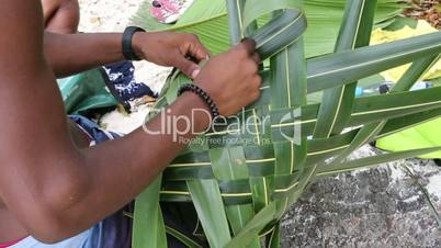 African builds basket from palm leaves