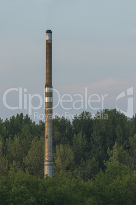 Factory chimney in a green environment.