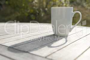 Drinking cup on a wooden table in the Sun.