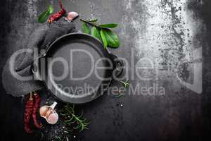 cast iron pan and spices on black metal culinary background, view from above