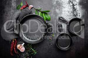 cast iron pan and spices on black metal culinary background, view from above