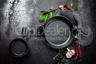 cast iron pan and spices on black metal culinary background, view from above