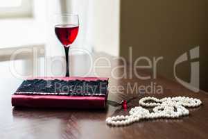 Book, glass of wine, beads