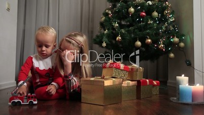 Happy children playing with toy by Christmas tree