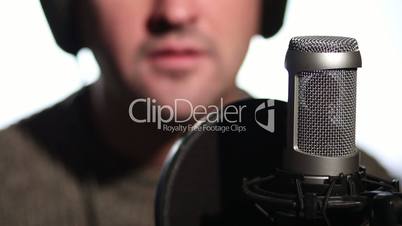 Close up man singing into a condenser microphone.