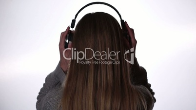 Back view of woman listening music in headphones
