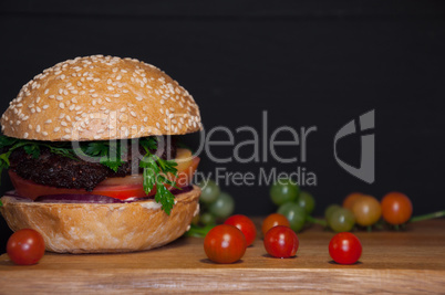 Tasty burger with meat cutlets served on a wooden board with che