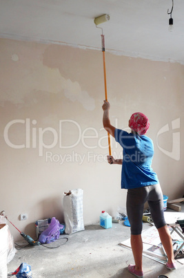 girl paints whitewash a ceiling, repair the apartment with his hands