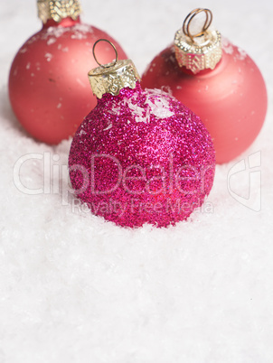 Pink Christmas baubles on snow