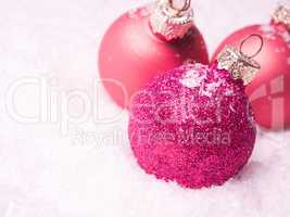 Three pink Christmas baubles in snow