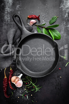 cast iron pan and spices on black metal culinary background, view from above