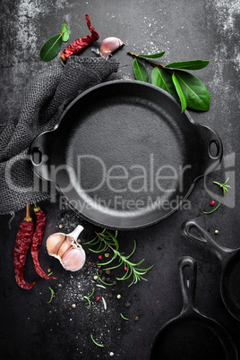 cast iron pan and spices on black metal culinary background, view from above