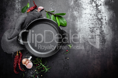 cast iron pan and spices on black metal culinary background, view from above