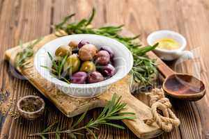 italian food ingredients, rosemary, olives, olive oil on wooden background