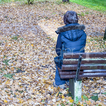 Woman sits only in autumn at the bank