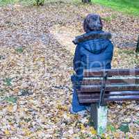 Woman sits only in autumn at the bank