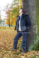 Woman leans in the tree and enjoys the autumn wood