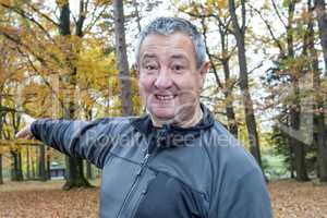 Man in the autumn wood points in a direction