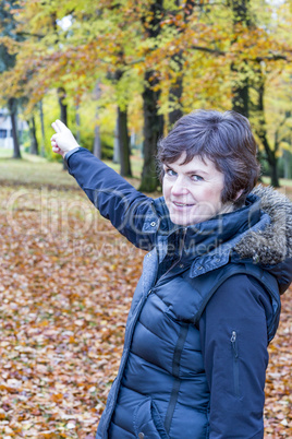 Woman in the autumn wood points in a direction