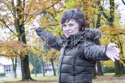 Woman in the autumn wood points in a direction