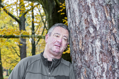 Man leans against tree to rest